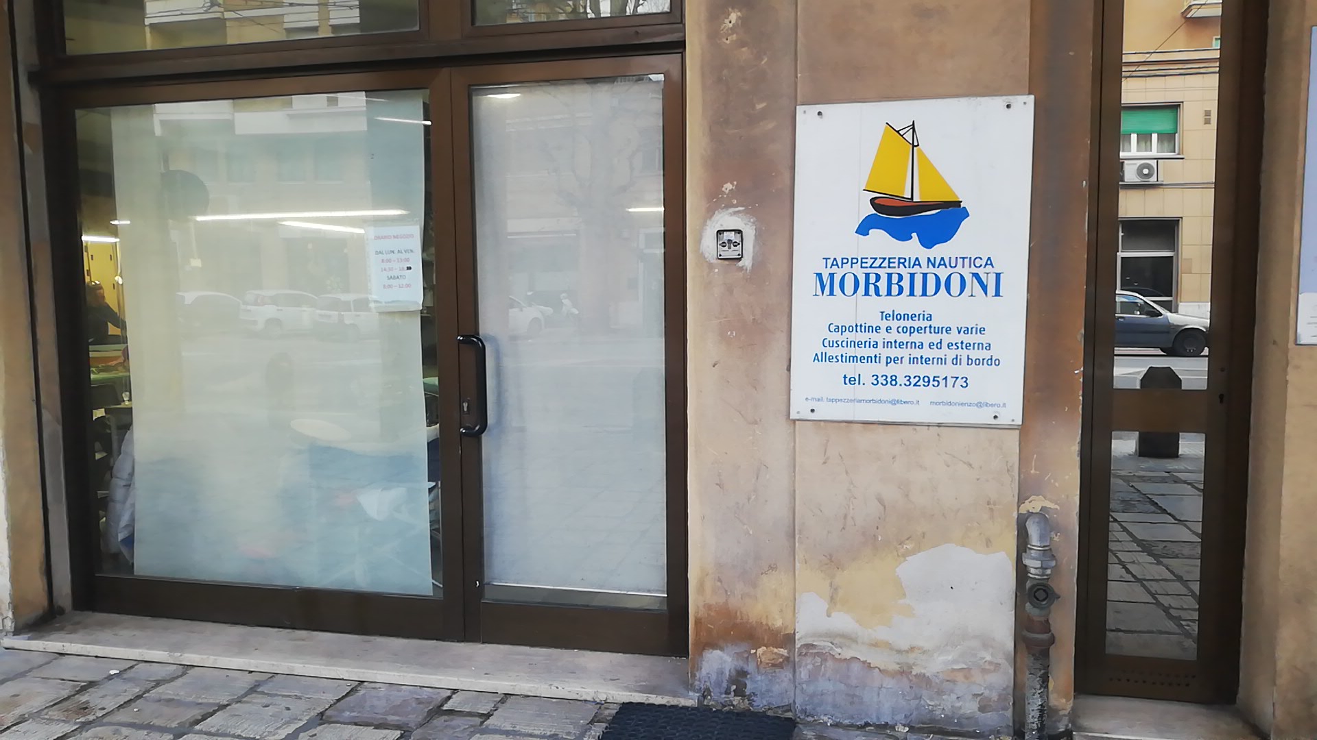 Vetrina della Tappezzeria Nautica Morbidoni e cartello degli orari